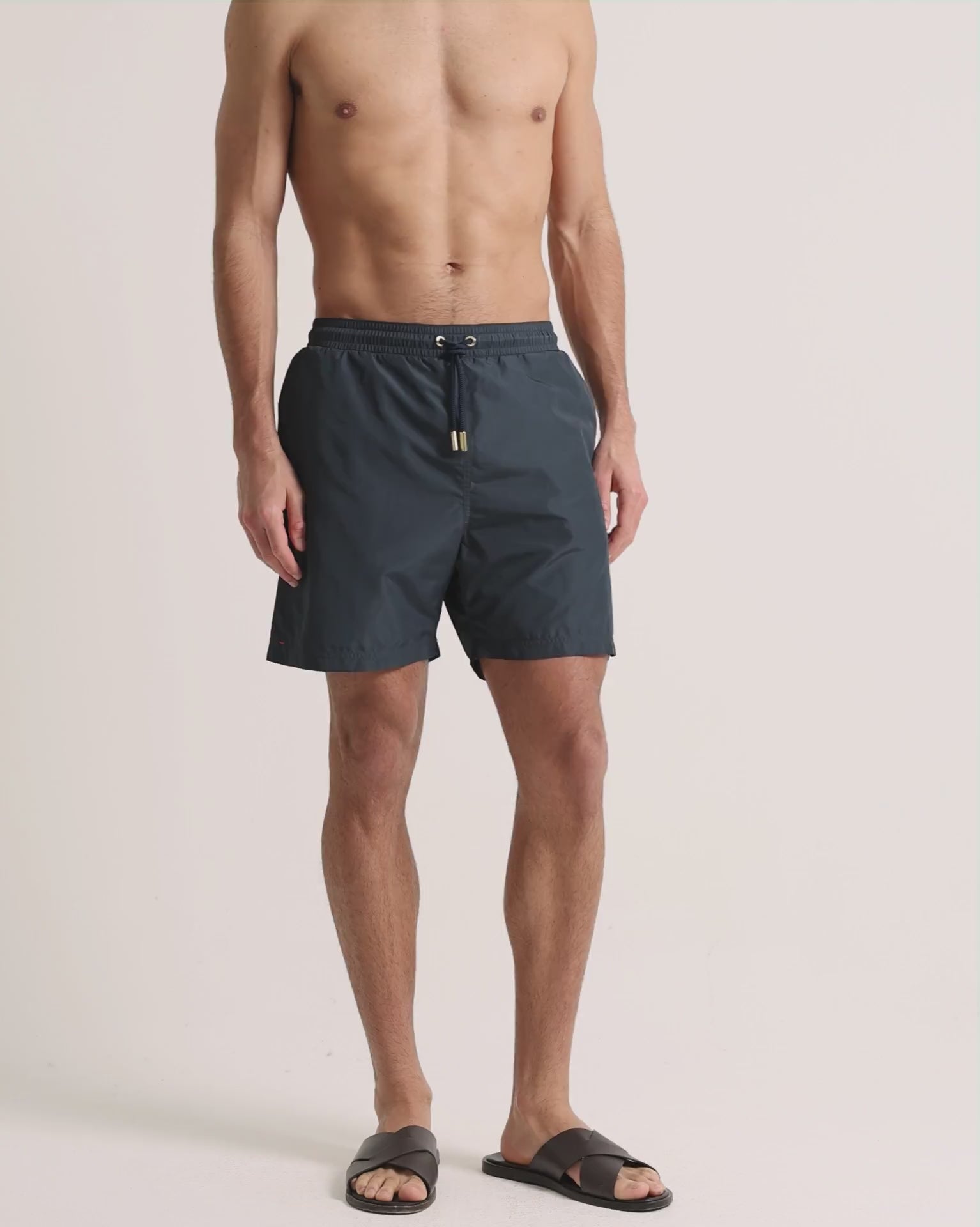 Man wearing grey swim shorts on a plain background
