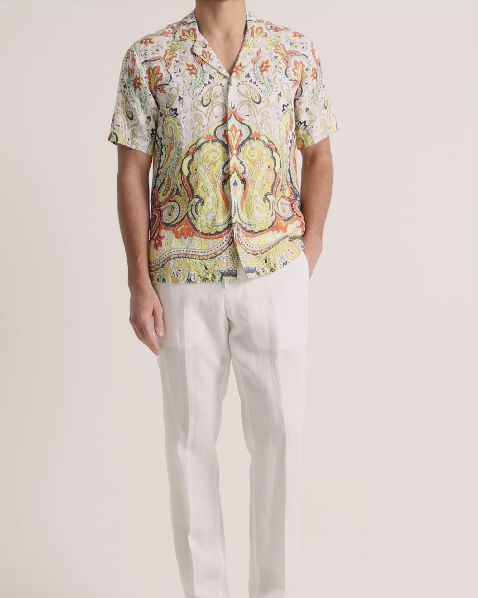 Man wearing printed linen shirt with white trousers on a plain background