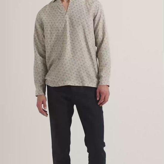 Man wearing patterned long sleeve shirt with dark navy trousers