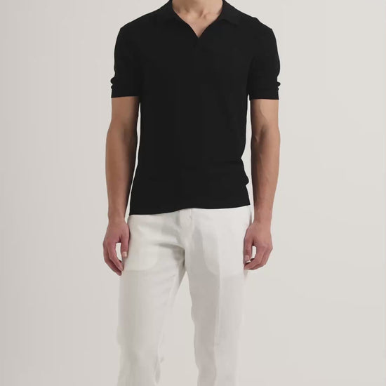 Man wearing black polo shirt with white trousers