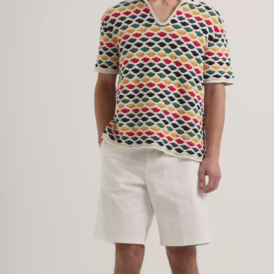 Man wearing multicolour crochet stitch polo shirt with white knee length shorts