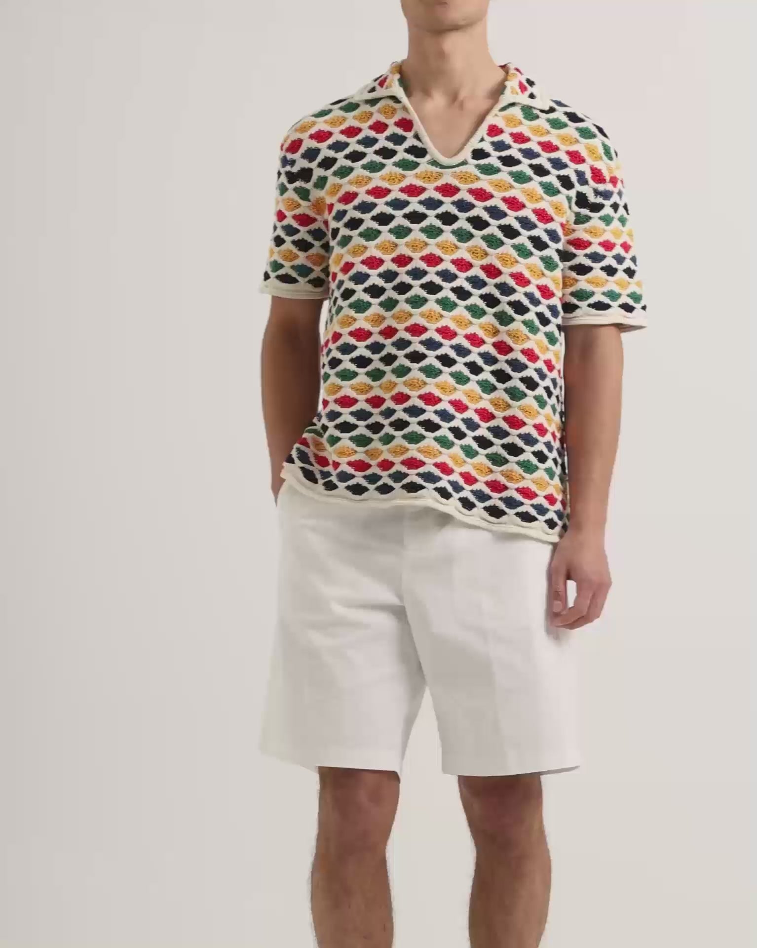 Man wearing multicolour crochet stitch polo shirt with white knee length shorts