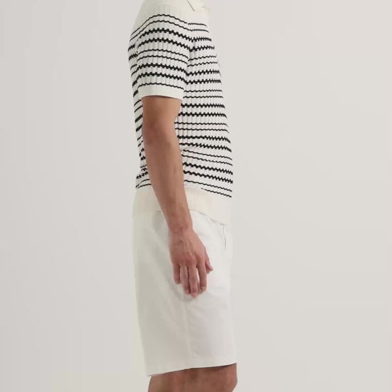Man wearing striped knitted polo shirt with white knee length shorts