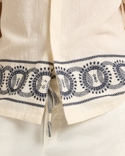 Close-up of a beige fabric with intricate black embroidery on a white background