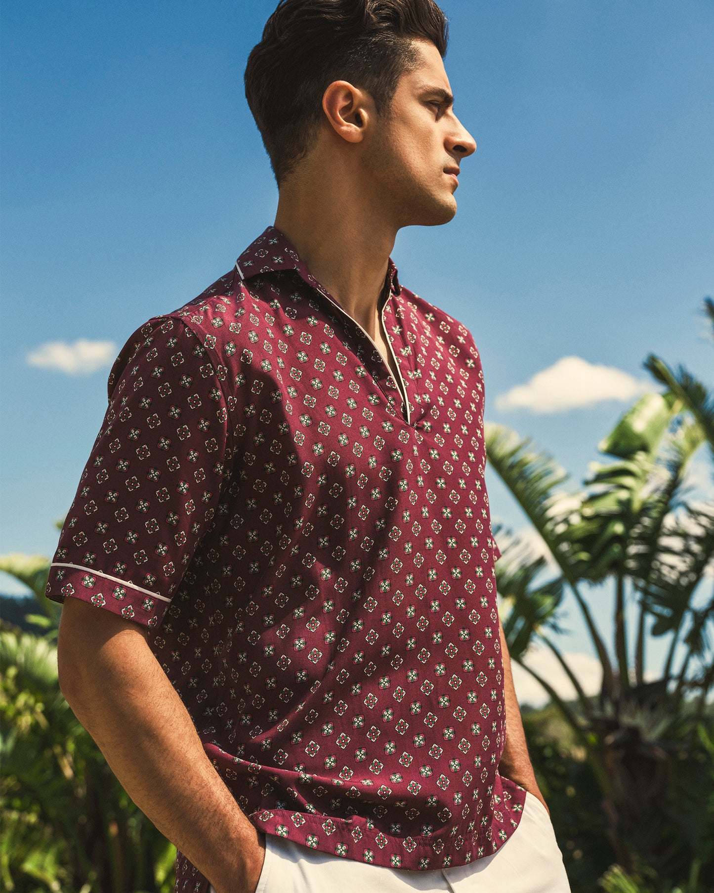 Man wearing a patterned shirt with palm trees in the background