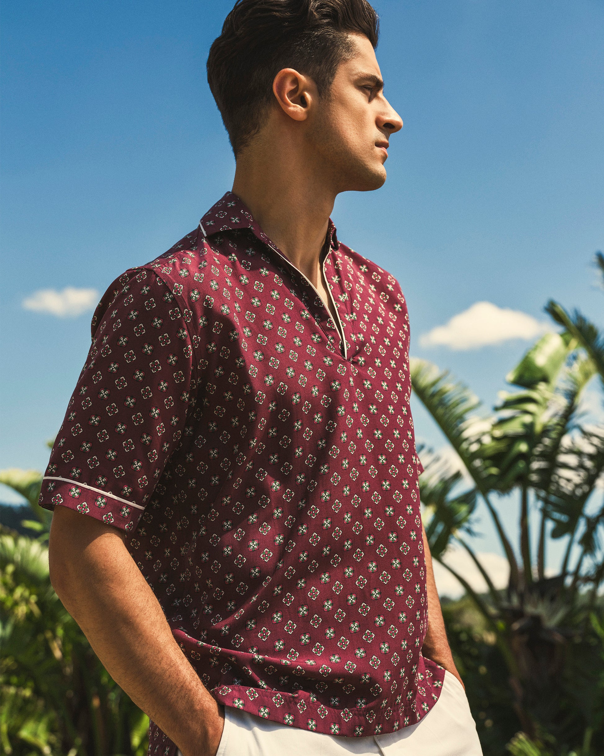 Man wearing a patterned shirt with palm trees in the background