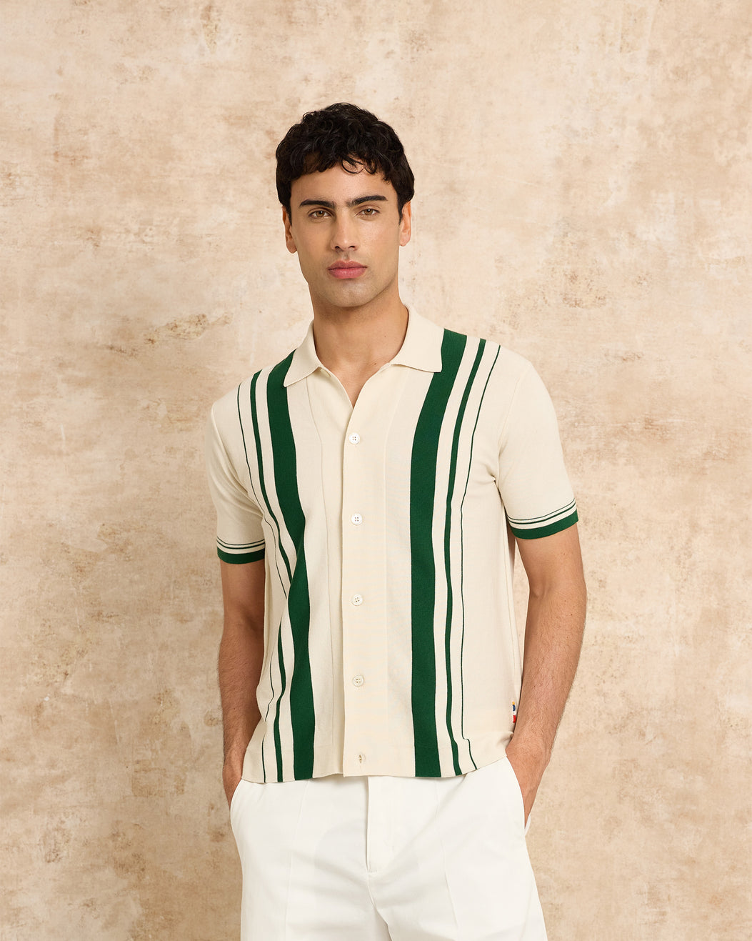 Man wearing a cream shirt with green stripes against a beige background