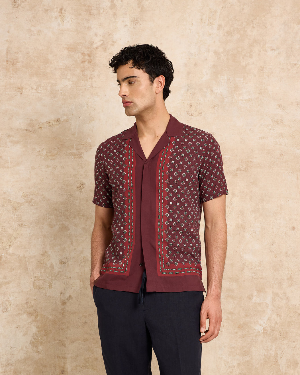 Man wearing a patterned shirt against a beige background