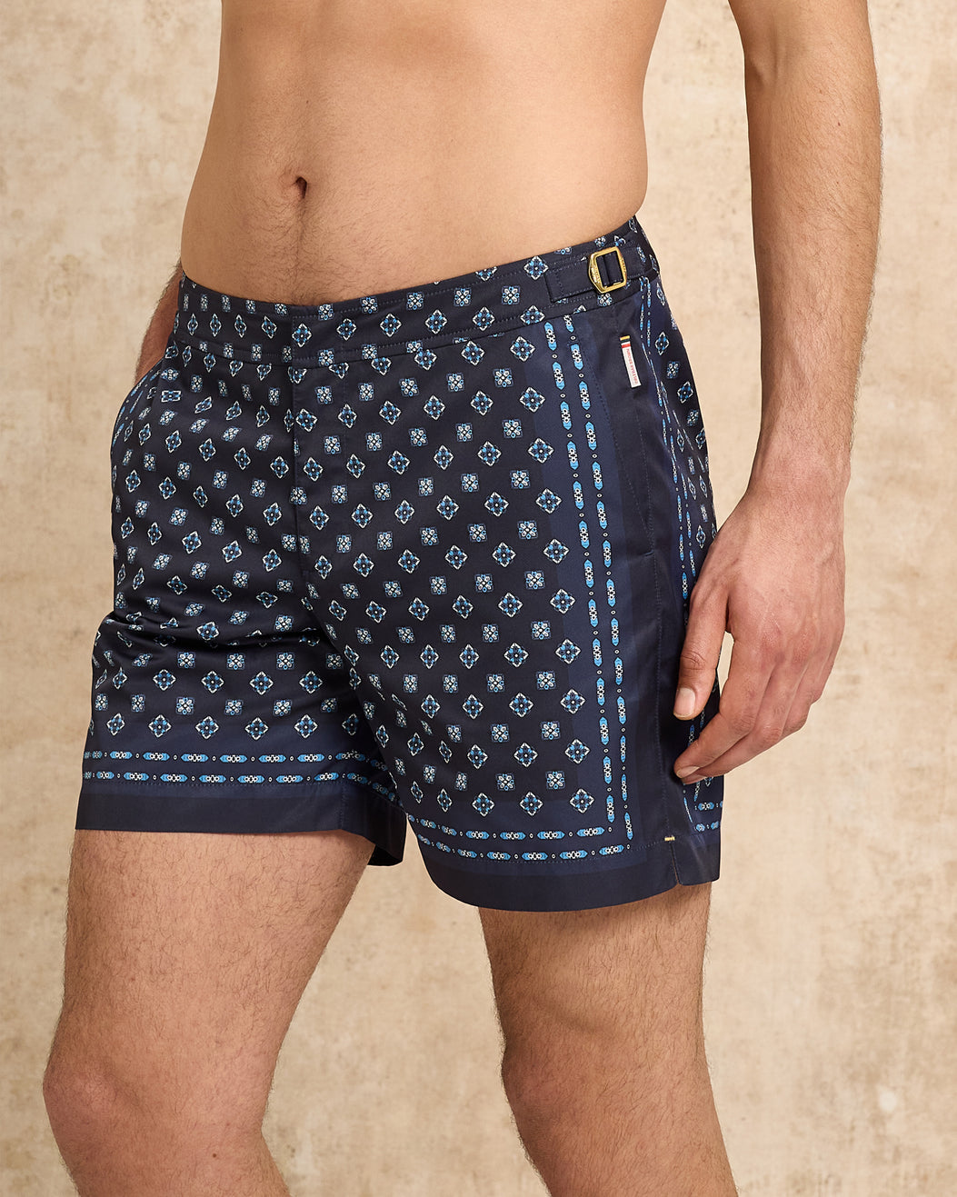Navy blue patterned swim shorts worn by a person on a beige background