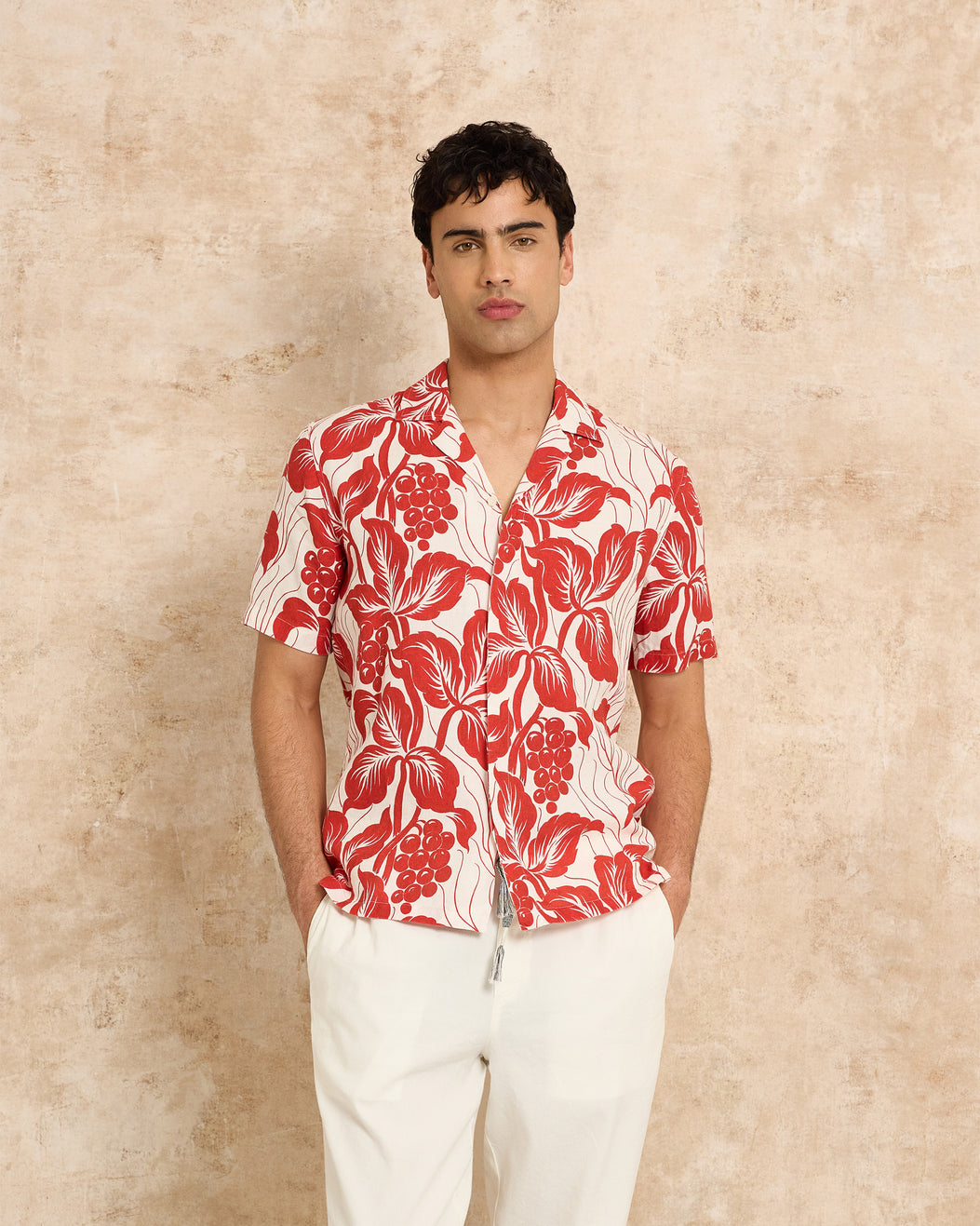 Man wearing a red and white floral shirt against a beige background