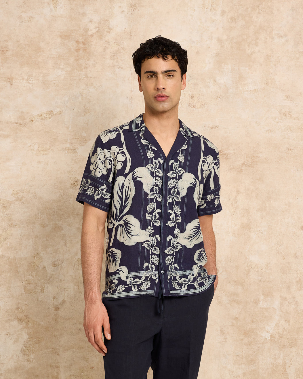 Man wearing a navy blue floral patterned shirt against a beige background